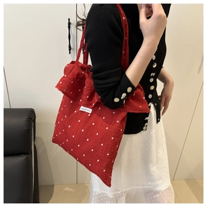 Detail of red polka dot mesh shoulder bag featuring ruffle trim and fragile pocket tag