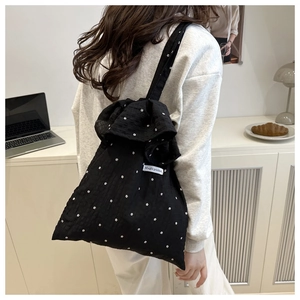 Detail of black floral mesh tote bag featuring a large bow and white flower patterns