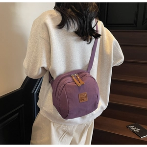 Détail du sac bandoulière en nylon violet avec plusieurs fermetures éclair et sangle