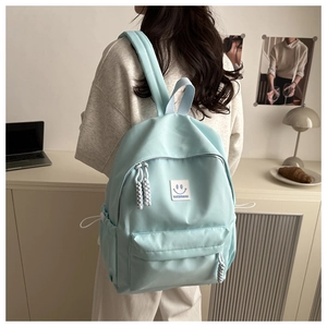 Detail of light blue nylon backpack with smile embroidery and woven rope zipper pull