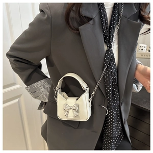 Detail of mini cream crossbody bag with silver bow accent and metallic chain strap