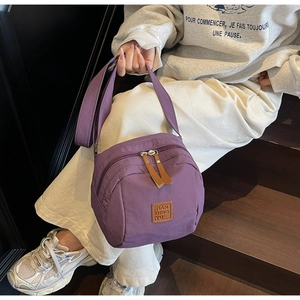 Gros plan sur un sac bandoulière en nylon violet avec double compartiment zippé et sangle