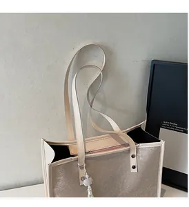 Detail of beige tote bag showing floral jacquard texture, zipper, and flower charm