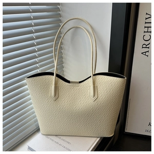 Detail of cream white tote bag featuring crocodile pattern and long slim leather handles