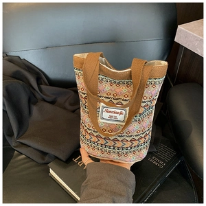 Détail du sac cabas tissé aux motifs ethniques avec de larges anses brunes sur cuir noir