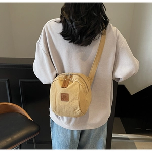 Détail du sac de poitrine vintage jaune avec double fermeture éclair et logo en cuir brun