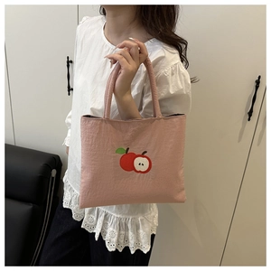 Detailed embroidery of a red apple on a pink nylon mini tote bag with double handles