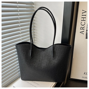 Detail of black woven tote bag with wavy rim texture and slim leather handles
