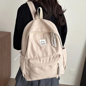 Minimalist beige nylon backpack for women featuring multiple pockets and a smiley face patch