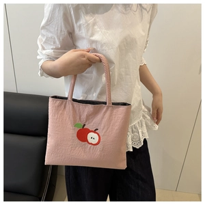 Detailed close-up of pink nylon handbag featuring vibrant red apple embroidery detail