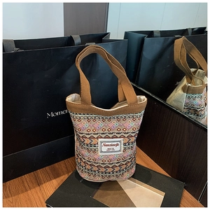 Détail d'un sac seau bohème avec motifs géométriques colorés et anses marron robustes