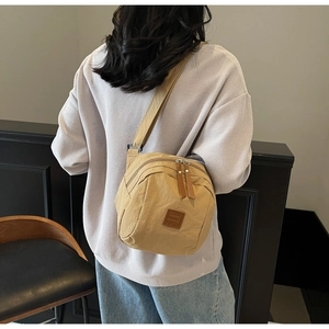 Détail d'un sac bandoulière en nylon kaki avec plusieurs zips et sangle réglable