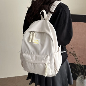 Cream white canvas backpack with smile patch and braided cord zippers in a casual style