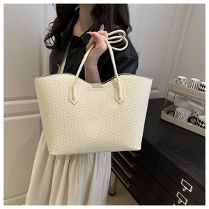 Close-up of the cream woven texture and slender shoulder straps of this large tote bag