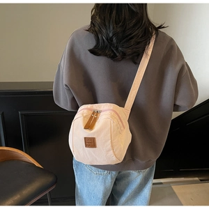 Détail du sac bandoulière en nylon rose avec sangle réglable et logo en cuir chic