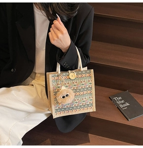 Close-up of ethnic woven tote with geometric patterns, cotton rope handle, and pompom charm