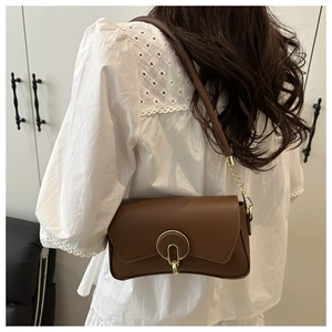 Close-up of small brown crossbody bag with gold buckle and wide shoulder strap
