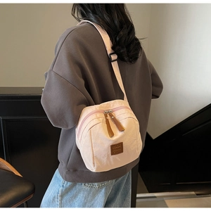 Vue arrière d'un mannequin portant le sac bandoulière beige clair avec détails en cuir
