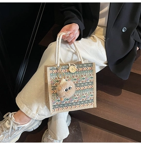 Detailed texture of ethnic tote bag with woven handles and fluffy charm on a wooden stair