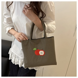 Detail of dark olive canvas tote featuring red apple embroidery and thick handles