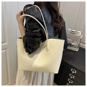 Detail of cream woven leather tote bag showing fine texture and slender straps