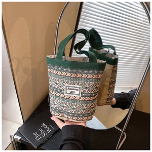 Détail d'un sac cabas tissé main avec motifs géométriques et poignées vertes