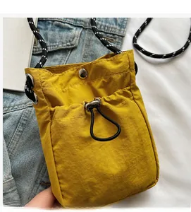 Close-up of bright yellow nylon crossbody bag featuring black and white rope strap detail
