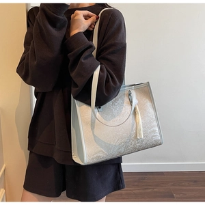 Detail of floral embossed texture and white tassel on large shoulder tote bag