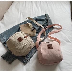 Gros plan de sacs bandoulière en nylon crème et rose avec sangles sur denim