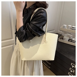 Detailed view of cream-colored woven texture tote bag worn as a shoulder bag