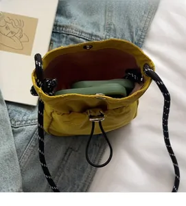 Detail view of mini yellow nylon bucket bag showing interior space with a mobile phone
