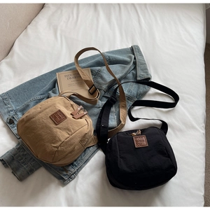 Vue à plat de sacs à bandoulière en nylon kaki et noir avec patch logo en cuir