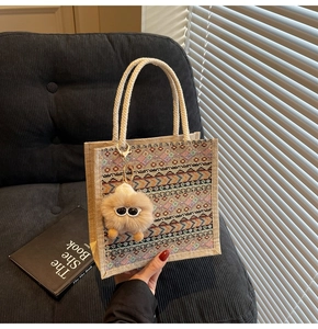 Ethnic woven tote bag featuring tribal geometric patterns and a plush doll pendant detail