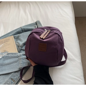 Détail d'un sac à dos multifonction en nylon violet avec étiquette cuir et zip métal