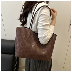 Detail of dark brown woven leather tote bag texture and long shoulder straps