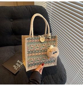 Detail of ethnic woven tote bag featuring geometric patterns and a plush monster charm
