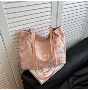 Detail of light pink lace tote bag with 3D butterfly embroidery and floral texture