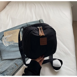 Détail du sac en nylon noir avec logo en cuir et système de fermeture à glissière double