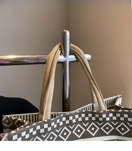 Close-up of geometric pattern canvas tote bag hanging on a metal stand with woven handles