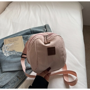 Gros plan détaillé du sac à dos en nylon rose avec logo en cuir et zip métallique de qualité