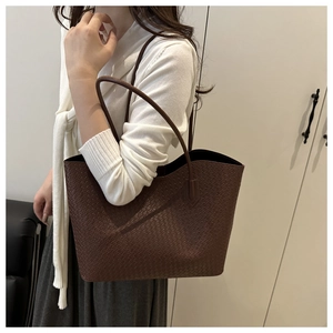 Detail of dark brown woven tote bag showing the texture and slender shoulder handle