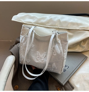 Detailed embroidery of white 3D butterfly appliques on a textured chic tote bag