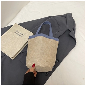 Détail d'un sac seau en paille tressée avec bordure en tissu bleu et texture en fibre