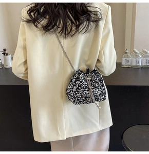 Dettaglio borsa a secchiello con paillettes nere, catena argento e coulisse con perle