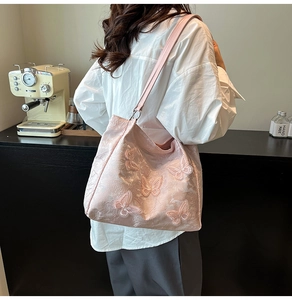 Detailed view of pink shoulder bag with intricate 3D butterfly embroidery and jacquard fabric