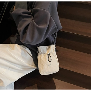 Close-up of cream drawstring phone bag in nylon material on a wooden staircase