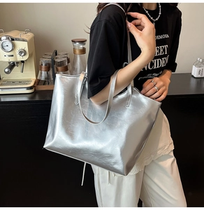 Side view of large silver metallic tote bag with natural leather texture worn by a model