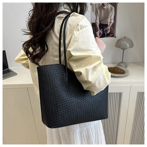 Detailed shot of a black woven tote bag styled with a yellow shirt and pleated skirt