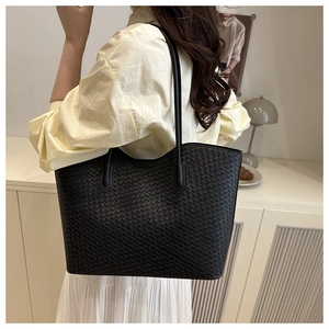 Detailed view of black woven tote bag worn on shoulder for daily commute style