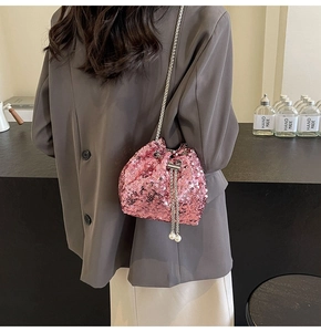 Borsa a secchiello con paillettes rosa e tracolla a catena in argento su una modella